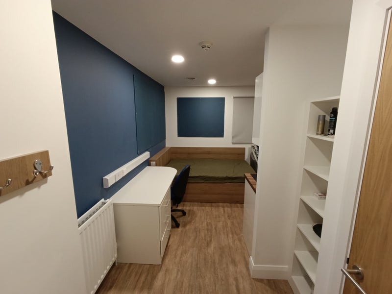 Photo 1: The entrance, bathroom to the right + bookshelf. Bed at the end with the side table