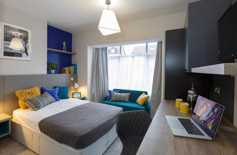 Photo 1: Ensuite bedroom with desk, minibar and sofa