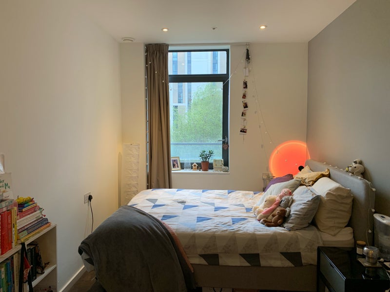 Photo 1: A close up of the bed by a large window that looks over a secure green courtyard and open sky