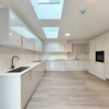 Photo 8: Bright and spacious communal kitchen featuring skylights, ample worktop space, and a stylish modern 