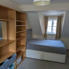 Photo 8: Room 2: shelf storage with containers and a side table. Double bed with 4 large drawers.