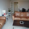 Photo 5: The living-room with two large leather sofas and large flatscreen TV and glass dining table.