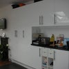 Photo 3: l-r  kitchen-lounge TV, fireplace, cupboards, toaster, slow-cooker 