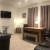 Photo 2: Living room with reclining sofas, TV, table and chairs.