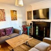 Photo 3: Lounge with two sofas, table, tv, fireplace, small table, cabinet and original art.
