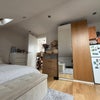 Photo 3: Bright loft room with skylights, double bed, built-in storage, and private fridge.